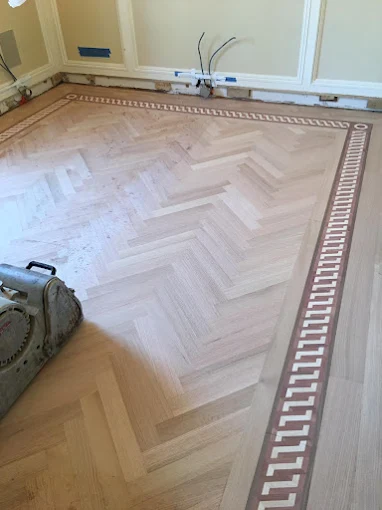 Sanded herringbone hardwood floor with decorative border